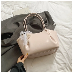 Détail du sac cabas en cuir verni rose clair avec nœud en dentelle et perles