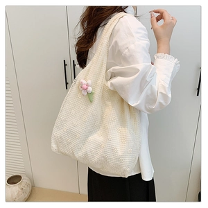 Detail of white floral lace tote bag with pink flower charm shown on model's shoulder