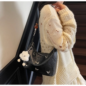 Détail du sac en cuir verni noir avec charmes papillons et pendentif en peluche blanche
