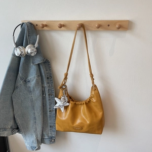 Detail of ginger leather pleated shoulder bag with silver star charm and knot strap