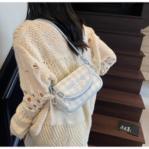 Detail showing the light blue checkered shoulder bag with pearl and lace accessories