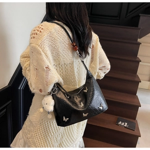 Détail d'un sac hobo avec papillons argentés et pendentif porté par un mannequin