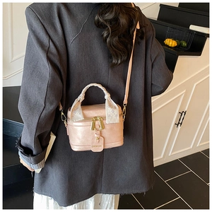 Modern pink bucket bag with silk scarf handle and golden hardware shown in lifestyle scene