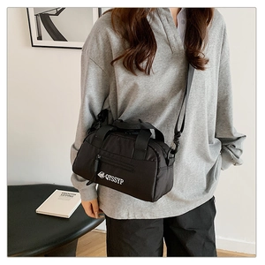 Gros plan sur un sac bandoulière en nylon noir avec logo blanc et poignées doubles
