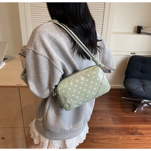 Polka dot underarm bag in light green with zipper closure shown on a model