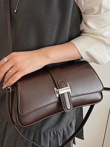 Minimalist deep brown rectangle shoulder bag with silver buckle worn by a model