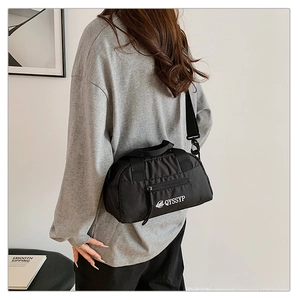 Détail d'un sac bandoulière en nylon noir avec sangle réglable et logo graphique blanc