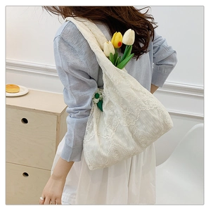 Close-up of white floral lace embroidery on a large canvas tote bag for women