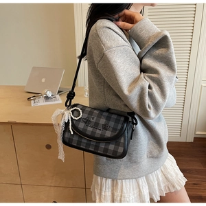 Close-up of retro checkered crossbody bag featuring lace bow and pearl handle details