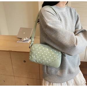 Detail of green polka dot shoulder bag with embossed letter B and stylish knotted strap