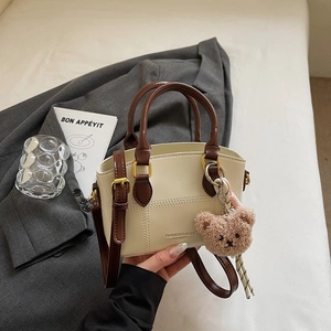 Detail der cremefarbenen Handtasche mit braunem Patchwork und goldener Hardware