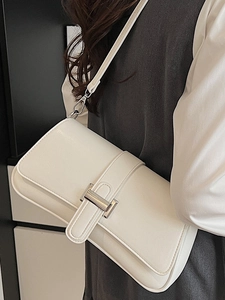 Minimalist white faux leather underarm baguette bag with silver buckle worn on shoulder