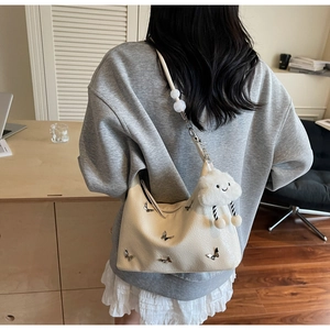 Détail du sac à bandoulière blanc cassé avec décor papillon et sangle perlée élégante