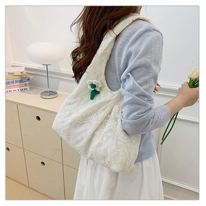 Close-up of white lace embroidery canvas tote bag with floral pendant on a shoulder bag