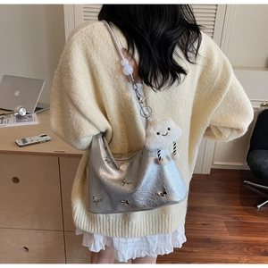 Détail du sac argenté avec papillon et pendentif nuage porté par un mannequin dans un bureau