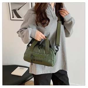 Sac bandoulière en nylon imperméable vert olive présenté dans un décor intérieur