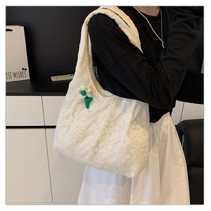 Detail view of white lace tote bag with floral embroidery and a green flower charm