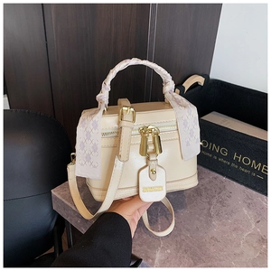 Detailed macro view of the beige box bag featuring a scarf-wrapped handle and golden hardware