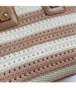 Close-up of woven bucket bag with cream and brown stripes, faux leather handle, and gold studs