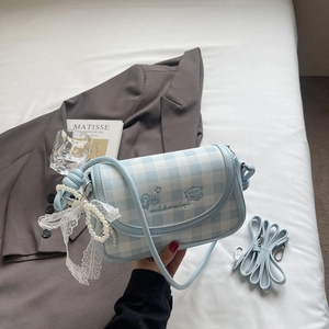Detail of light blue gingham handbag with pearl chain and lace bow on white bedding