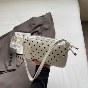 Close-up of white leather polka dot bag featuring an embossed B logo and knotted strap