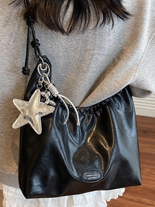 Fashionable black leather tote bag with silver star pendant and pleated detail