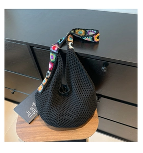 Détail d'un sac hobo au crochet noir à mailles avec une bandoulière à fleurs colorées