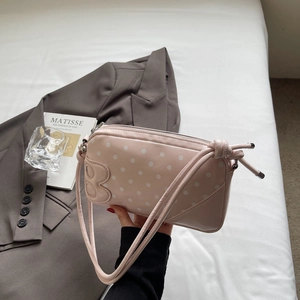 Detail of pink polka dot baguette bag featuring a metallic B logo and knotted strap