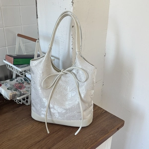 Close-up of cream jacquard tote bag with butterfly texture and ribbon bow detail