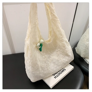 Close-up of white lace canvas tote with floral embroidery and green tulip pendant