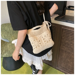 Détail du motif floral au crochet sur le sac à bandoulière en paille beige à franges