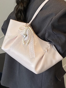 Sac fourre-tout en cuir verni rose avec nœud en dentelle et perles porté à l'épaule