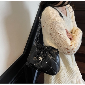 Détail d'un sac à bandoulière matelassé noir orné de strass argentés et d'une boucle étoile