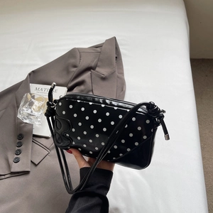 Close-up of black polka dot faux leather shoulder bag with embossed letter B detail