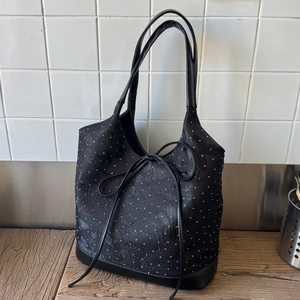 Detail of black tote bag with white polka dots, floral jacquard, and leather straps