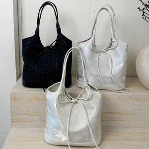 Three minimalist tote bags in black and silver featuring bow accents and texture details
