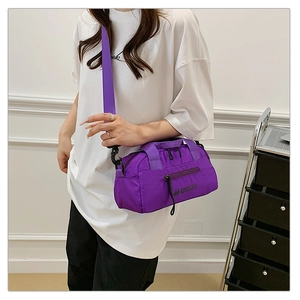 Détail du sac bandoulière en nylon violet avec forme cylindrique et sangle réglable amovible