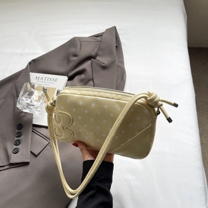 Close-up of yellow polka dot shoulder bag with glossy finish and B letter detail