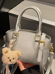 Silberne Stepphandtasche mit goldenen Beschlägen und niedlichem Bärenanhänger