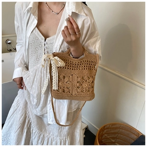 Détail du sac en paille fait main avec fleurs ajourées et nœud en dentelle blanche
