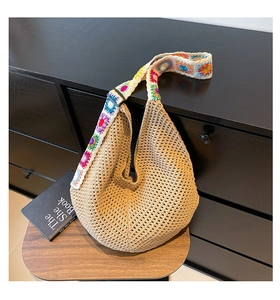 Détail macro du sac cabas en paille kaki avec bandoulière brodée à fleurs bohèmes