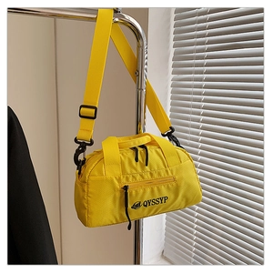 Détail d'un sac bandoulière en nylon jaune vif imperméable suspendu dans un décor intérieur