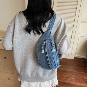 Détail du sac bandoulière en denim avec fermeture à franges et texture de tissu délavé