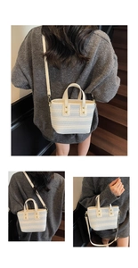 Close-up of woven perforated cream tote bag with adjustable strap and golden hardware