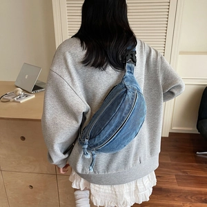 Vue arrière d'un mannequin portant un grand sac bandoulière en denim bleu avec fermetures