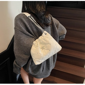 Détail du sac matelassé crème avec boucle étoile et bandoulière chaîne sur escalier