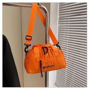 Détail du sac bandoulière en nylon orange avec texture matelassée et bretelles réglables
