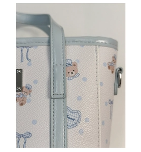 Detail of light blue faux leather handbag with cute cartoon bear print and pebbled texture