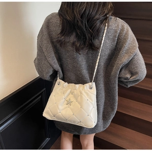 Détail d'un sac à bandoulière matelassé blanc avec une étoile scintillante en strass