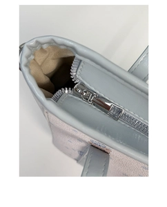 Close-up of light blue tote bag showing the metal zipper closure and cartoon print detail